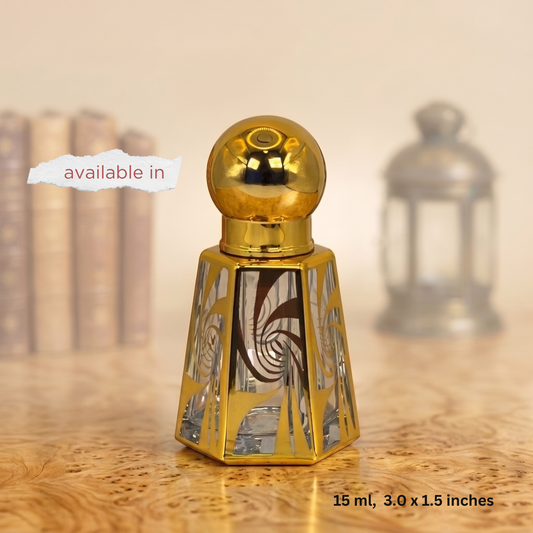 A small decorative perfume bottle with a shiny gold spherical cap and a faceted gold base featuring mirrored geometric patterns, shown on a wooden surface with a softly blurred background. Text overlays read 'available in' and '15 ml, 3.