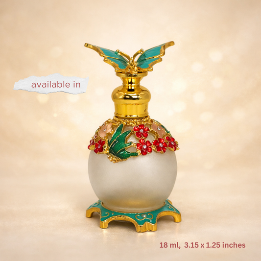 A decorative perfume bottle with a frosted white glass body, gold-tone metal detailing, turquoise accents, and red floral embellishments, shown on a warm beige background with 'available in' text and size information.