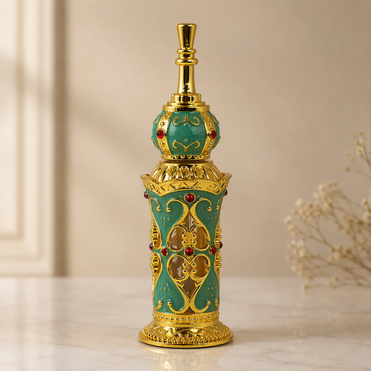 An ornate perfume bottle with a turquoise enamel body, gold-plated metal detailing, and small red gemstone accents, set on a light marble surface with a soft beige background.