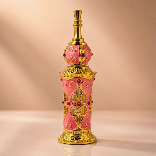 An ornate pink and gold perfume bottle with decorative filigree and red gem accents, centered on a warm beige background.