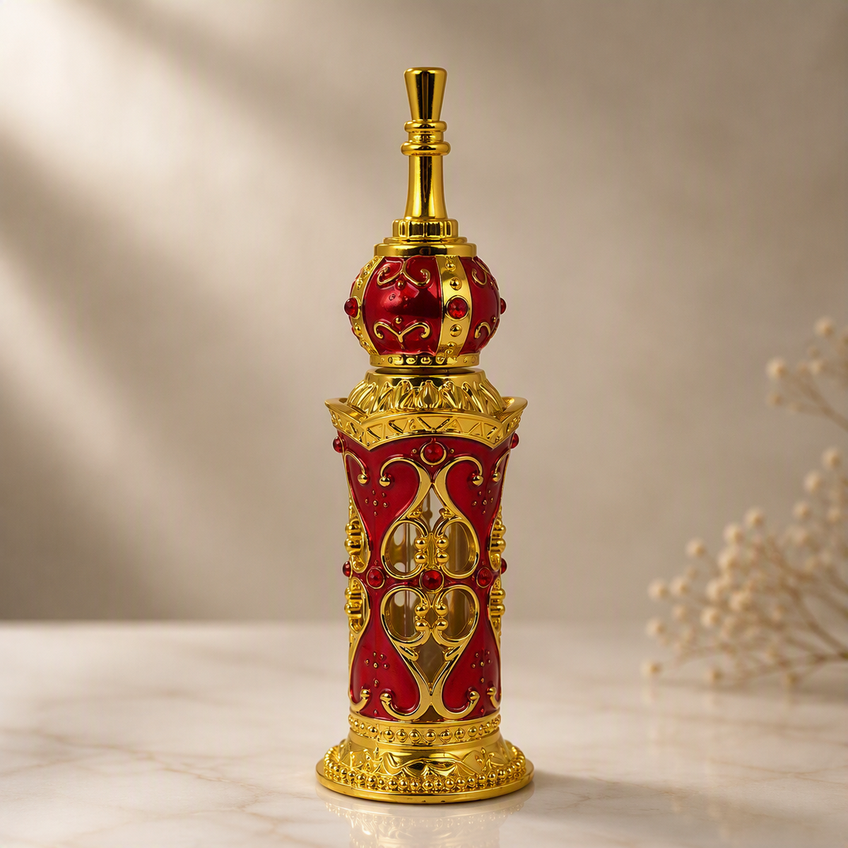 An ornate red and gold decorative bottle with a crown-like top and intricate scrollwork, photographed on a light marble surface against a soft beige background.