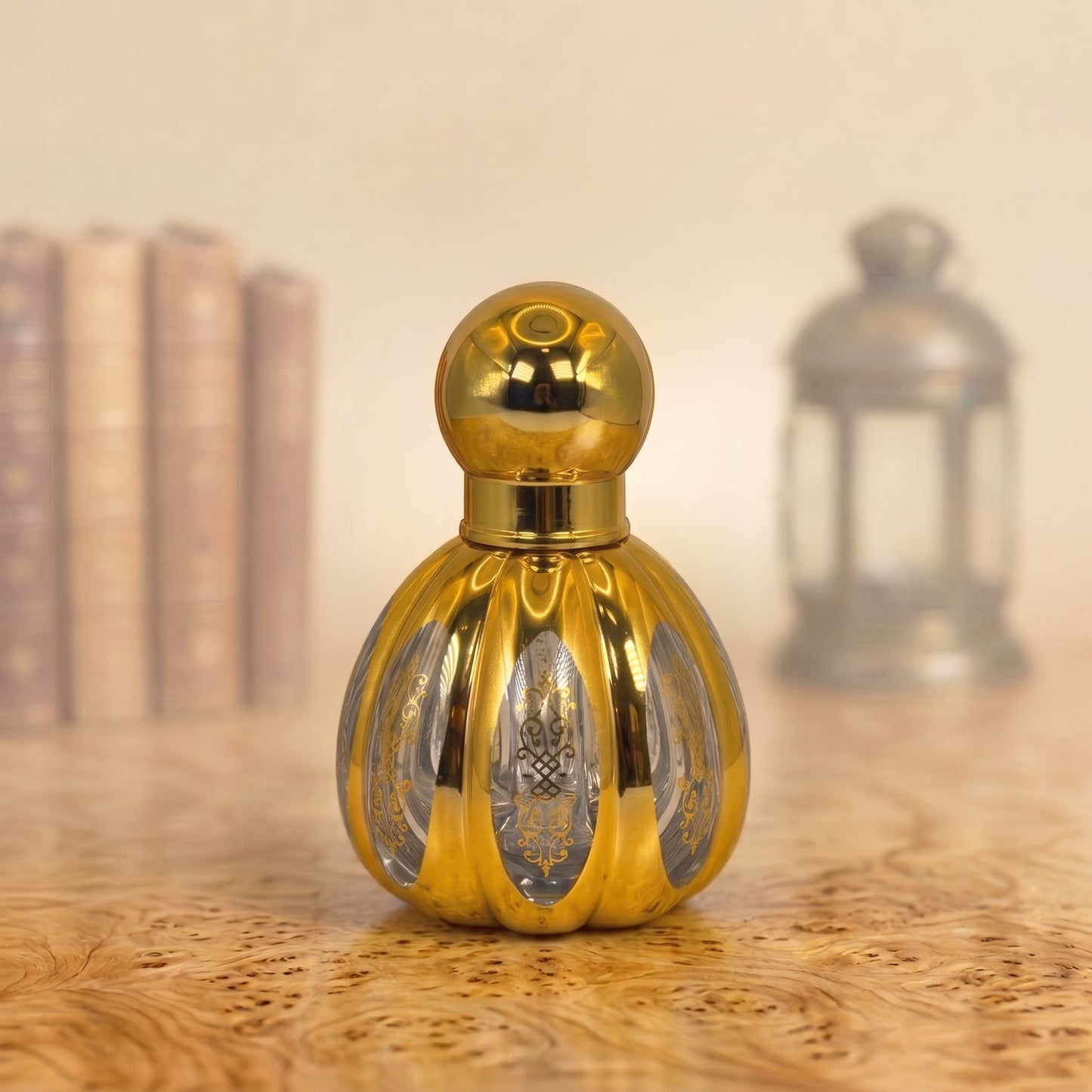 A small ornate gold perfume bottle with a spherical cap and ribbed body, standing on a wooden surface with a softly blurred background featuring books and a lantern.
