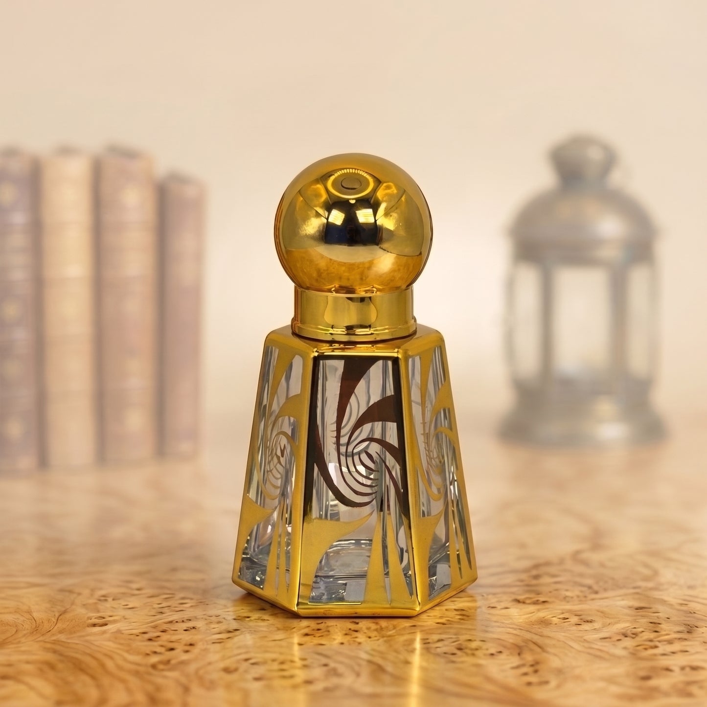 A decorative perfume bottle with a polished gold spherical cap and a faceted gold base featuring mirrored glass panels with abstract brown and silver patterns, set on a wooden surface with a softly blurred background.