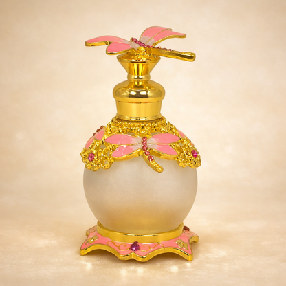 Decorative perfume bottle with gold and pink accents on a beige background